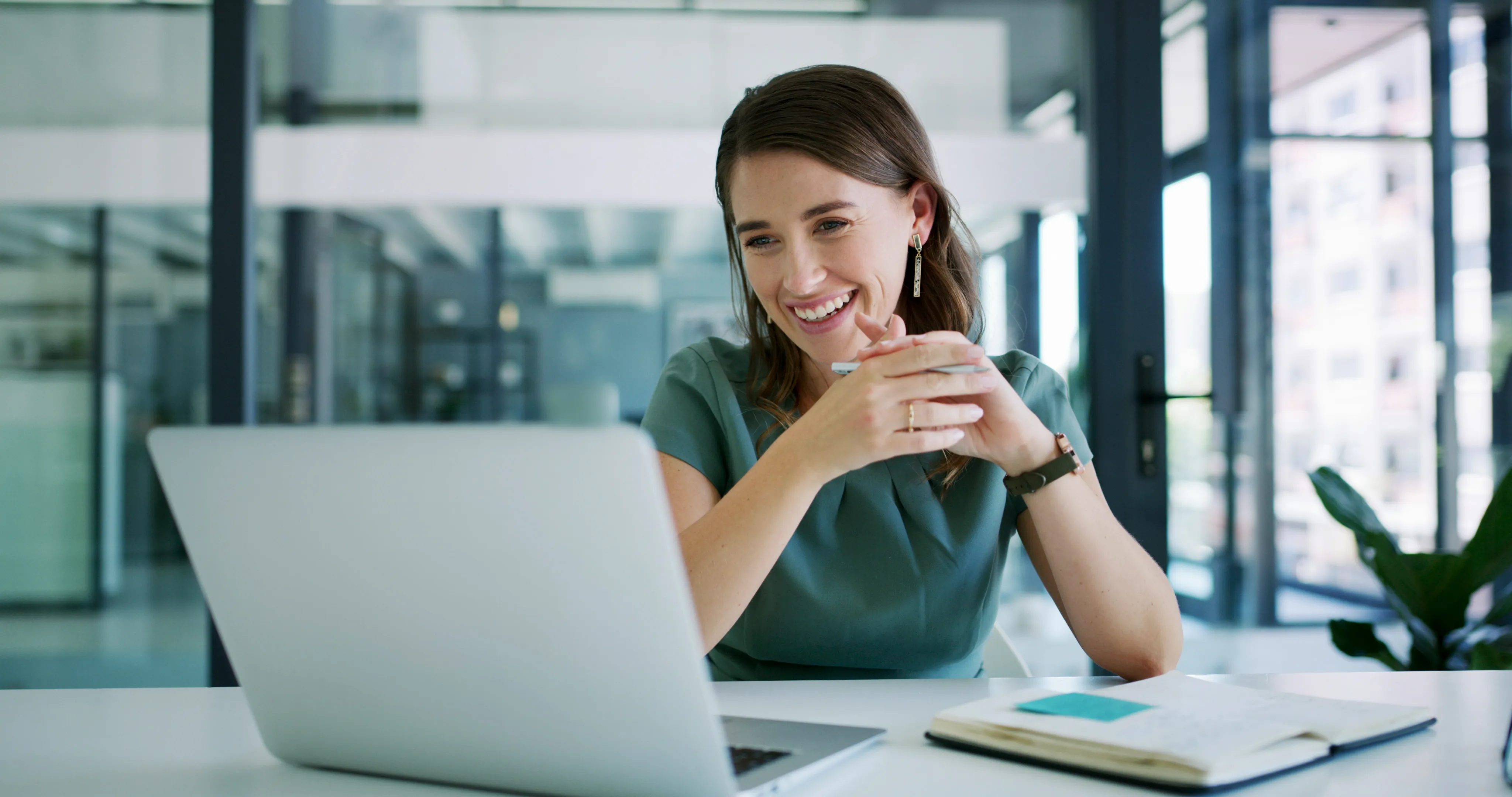A leader smiling during a one-to-one video conversation at her desk