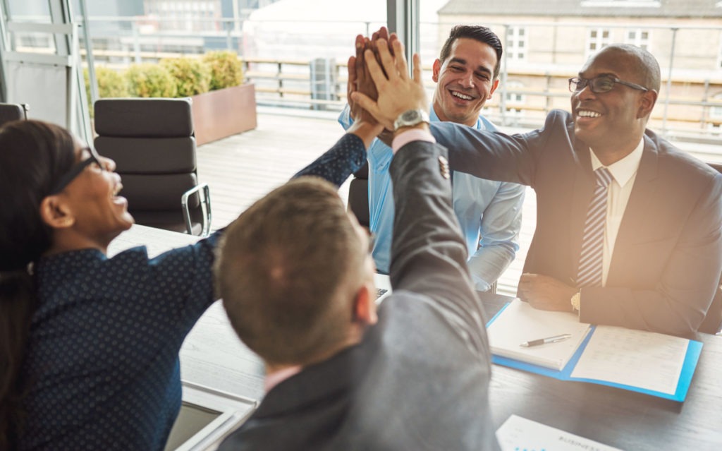 Exultant team of business professionals Exultant team of multiracial young business professionals rejoicing and congratulating each other giving a high fives gesture