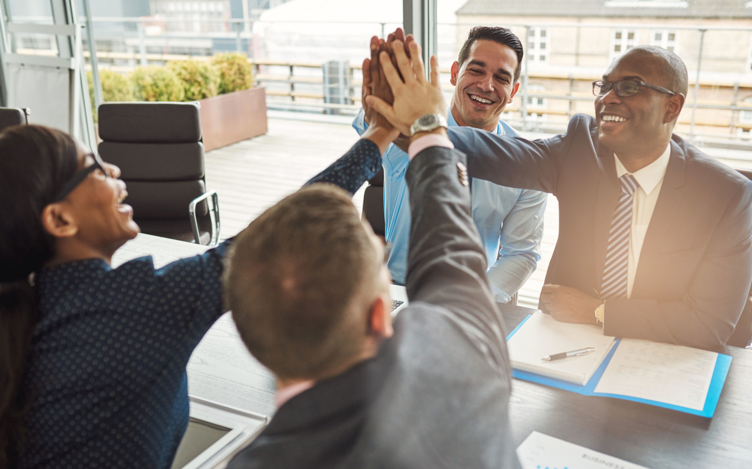 Exultant team of business professionals Exultant team of multiracial young business professionals rejoicing and congratulating each other giving a high fives gesture