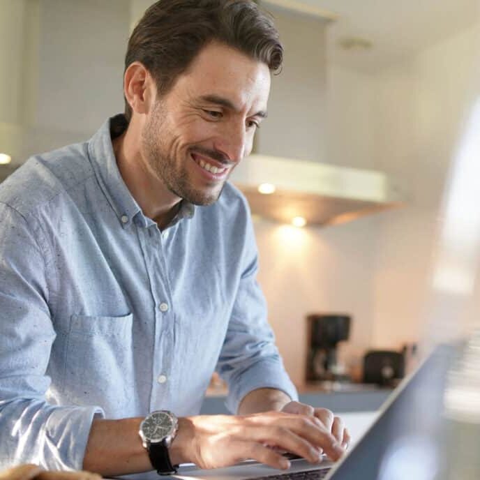 Handsome man with computer in modern kitchen